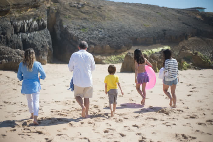 A family walking down the sand carrying floats