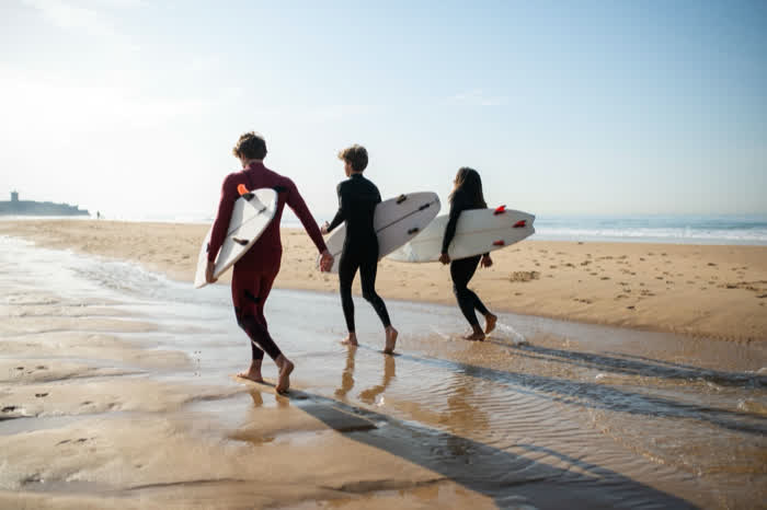 Three surfers walking into the shallows with their boards
